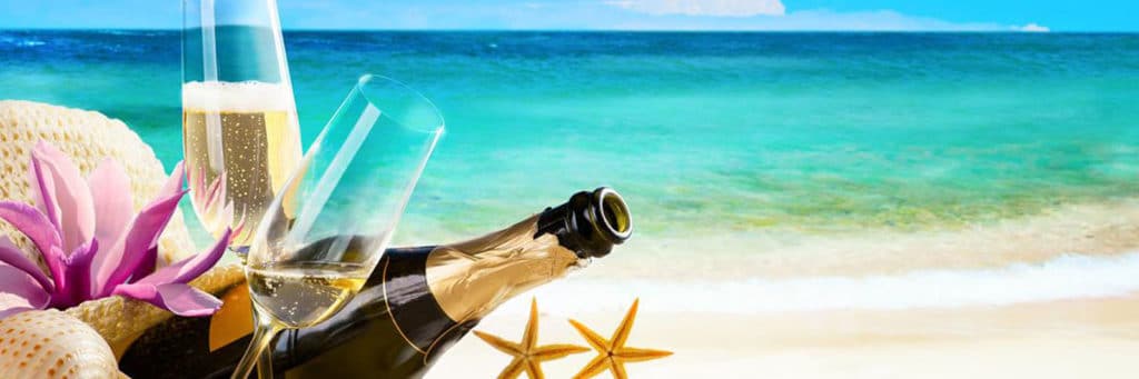 Garrafa de champagne, duas taÃ§as e demais decoraÃ§Ãµes de praia Ã  beira do mar, na faixa de areia, imagem em destaque do blog da Pousada dos Sonhos