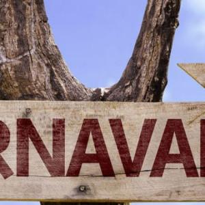 Placa com a palavra carnaval, apontando para direita, com praia ao fundo