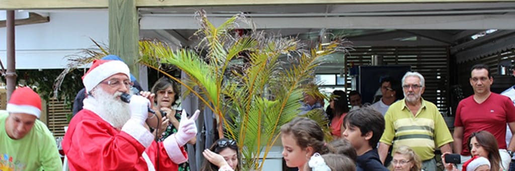 Diversas crianÃ§as aglomeradas frente ao restaurante da Pousada dos Sonhos para receber seus presentes do Papai Noel