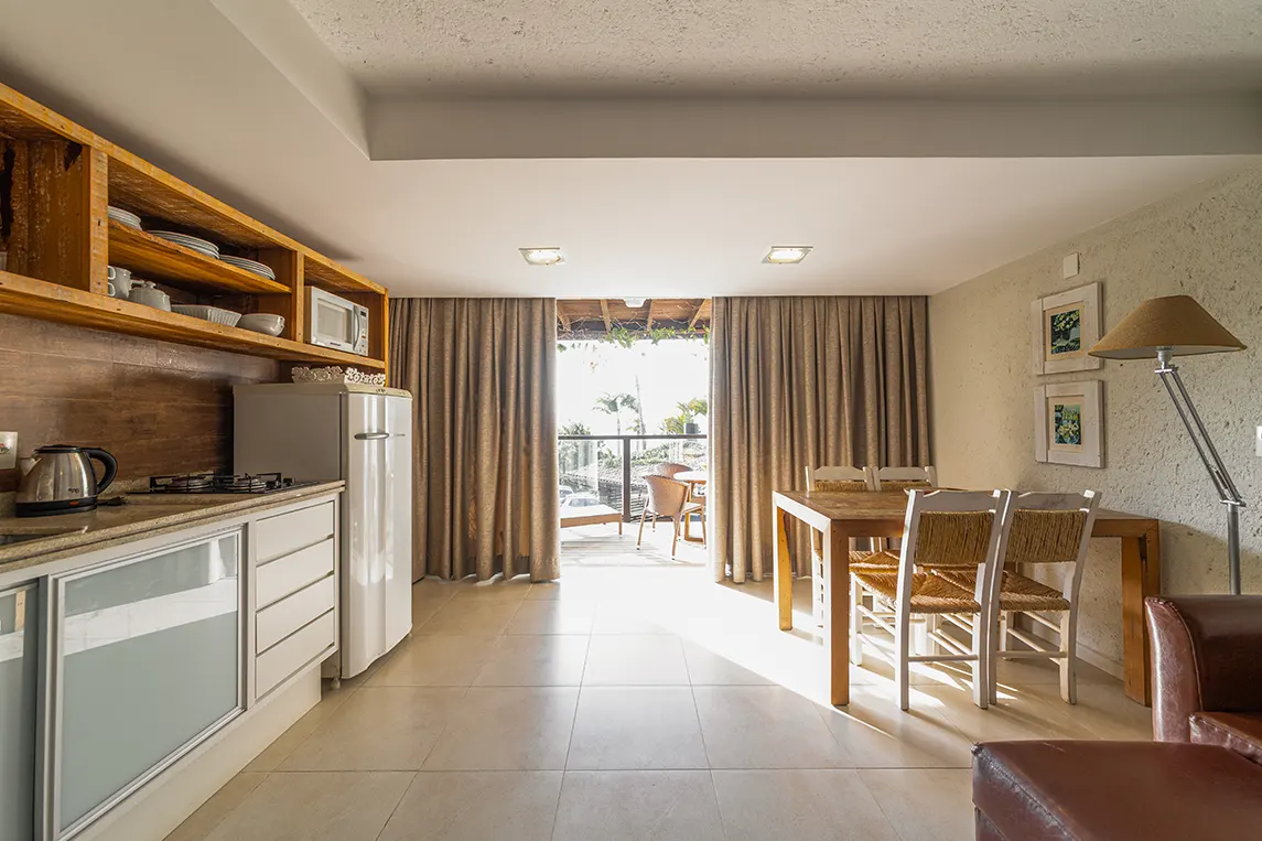 Sala de estar e cozinha integrada com sacada e bela vista de Jurerê no Apartamento Luxo da Pousada dos Sonhos em Florianópolis, Santa Catarina