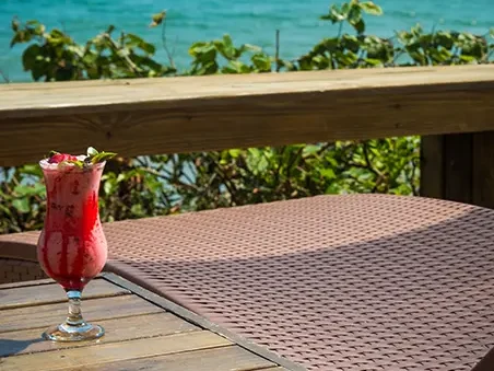Um delicioso drink de frutas é servido em deck elevado frente ao mar de Jurerê em Florianópolis em Santa Catarina, com vista para a Ilha do Campeche. Oportunidades assim você só encontra na Pousada dos Sonhos!