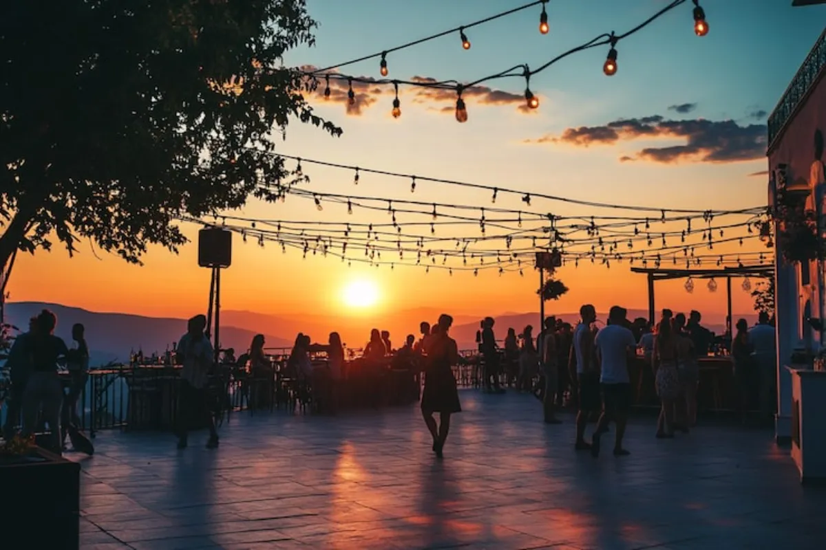 Eventos em Florianópolis ao ar livre durante o pôr do sol, com pessoas reunidas e iluminação decorativa.